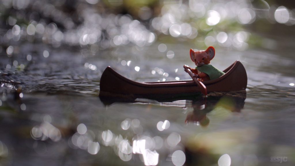 A lego version of the Mouse Guard character Lieam journeys down the sparkling river in his Lego canoe.