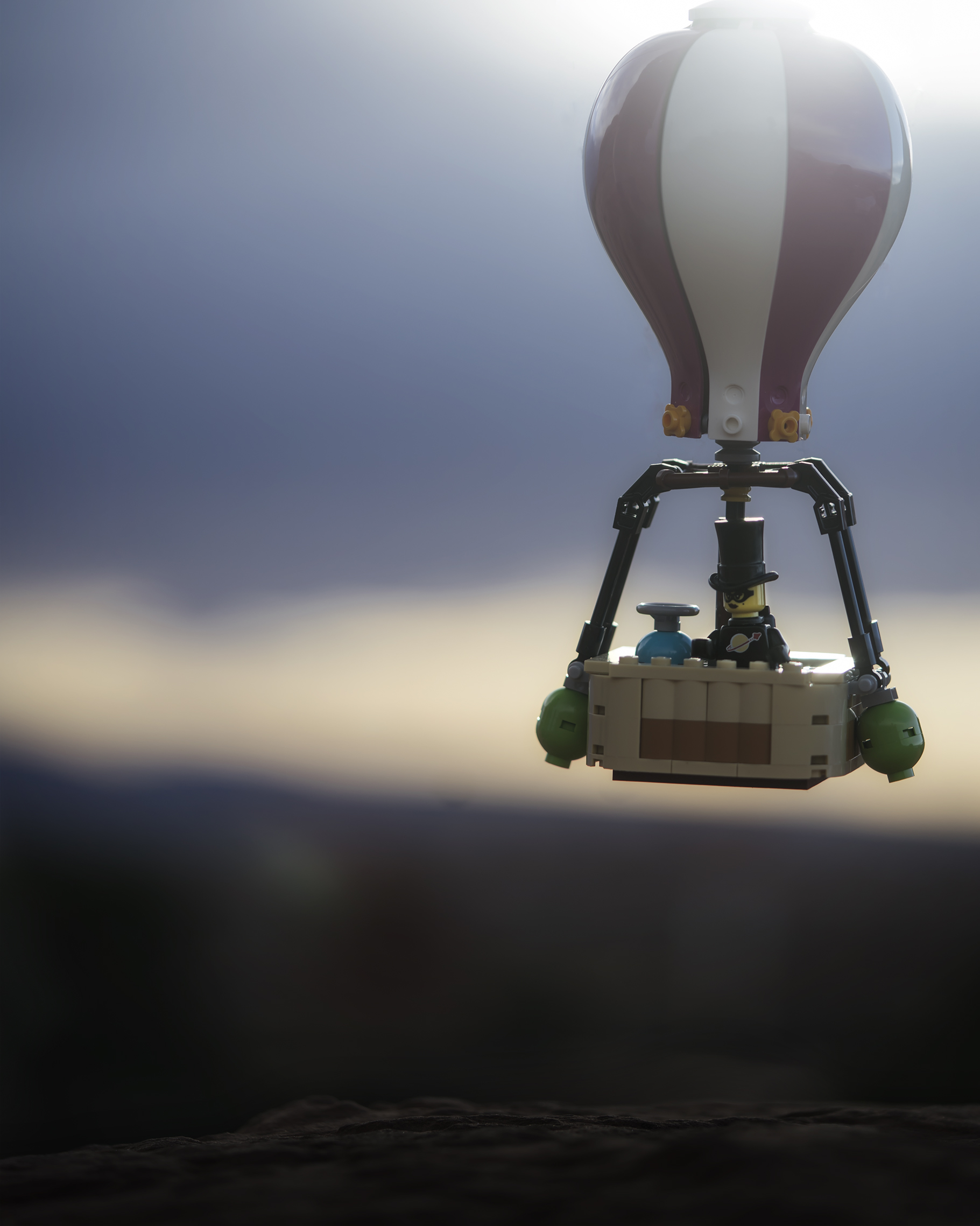 LEGO hot air ballon floats in the air with dark clouds looming in the distance. 