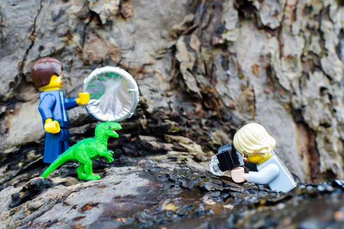 LEGO figures taking photos of toy dinosaur