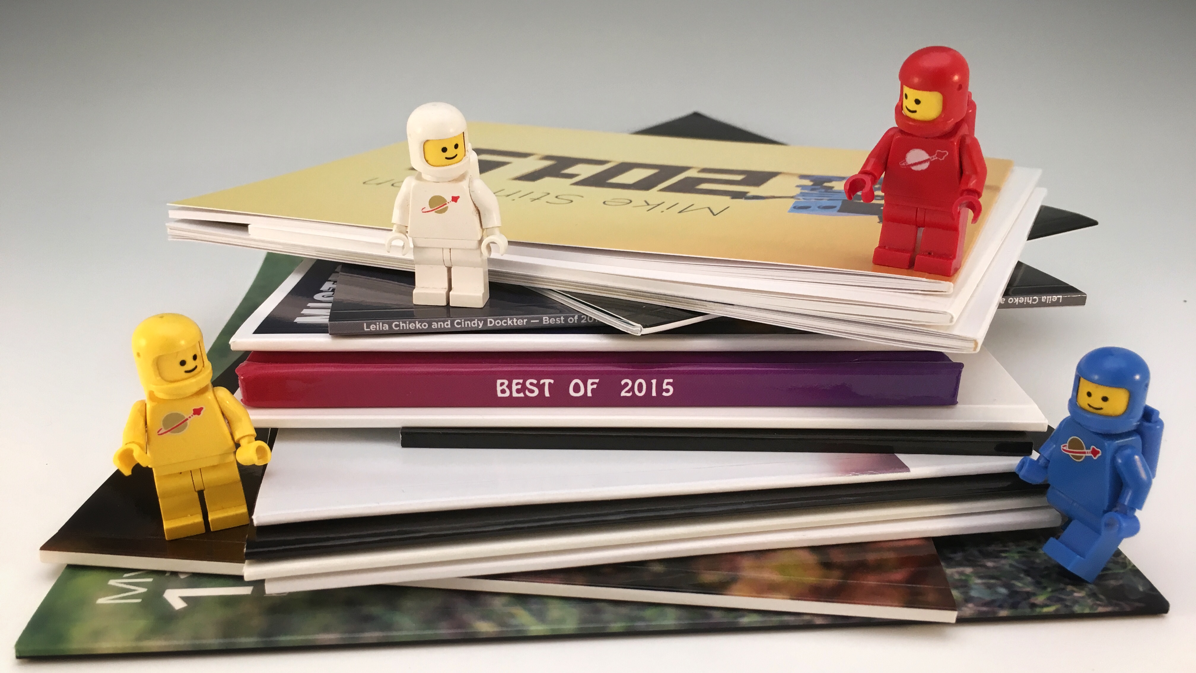 15 toy photography books in a short stack with four classic lego spacemen.