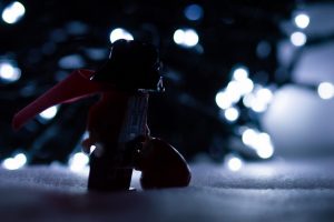 Darth Santa delivering Christmas presents in front of lit tree