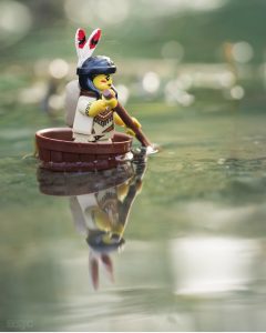 LEGO Indian maiden paddles her craft across the pond is reflected in the water. photo by Shelly Corbett