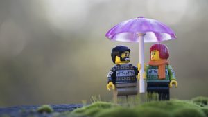 Two LEGO minifigures stand under a pink umbrella in their Christmas sweaters. Photo by Shelly Corbett