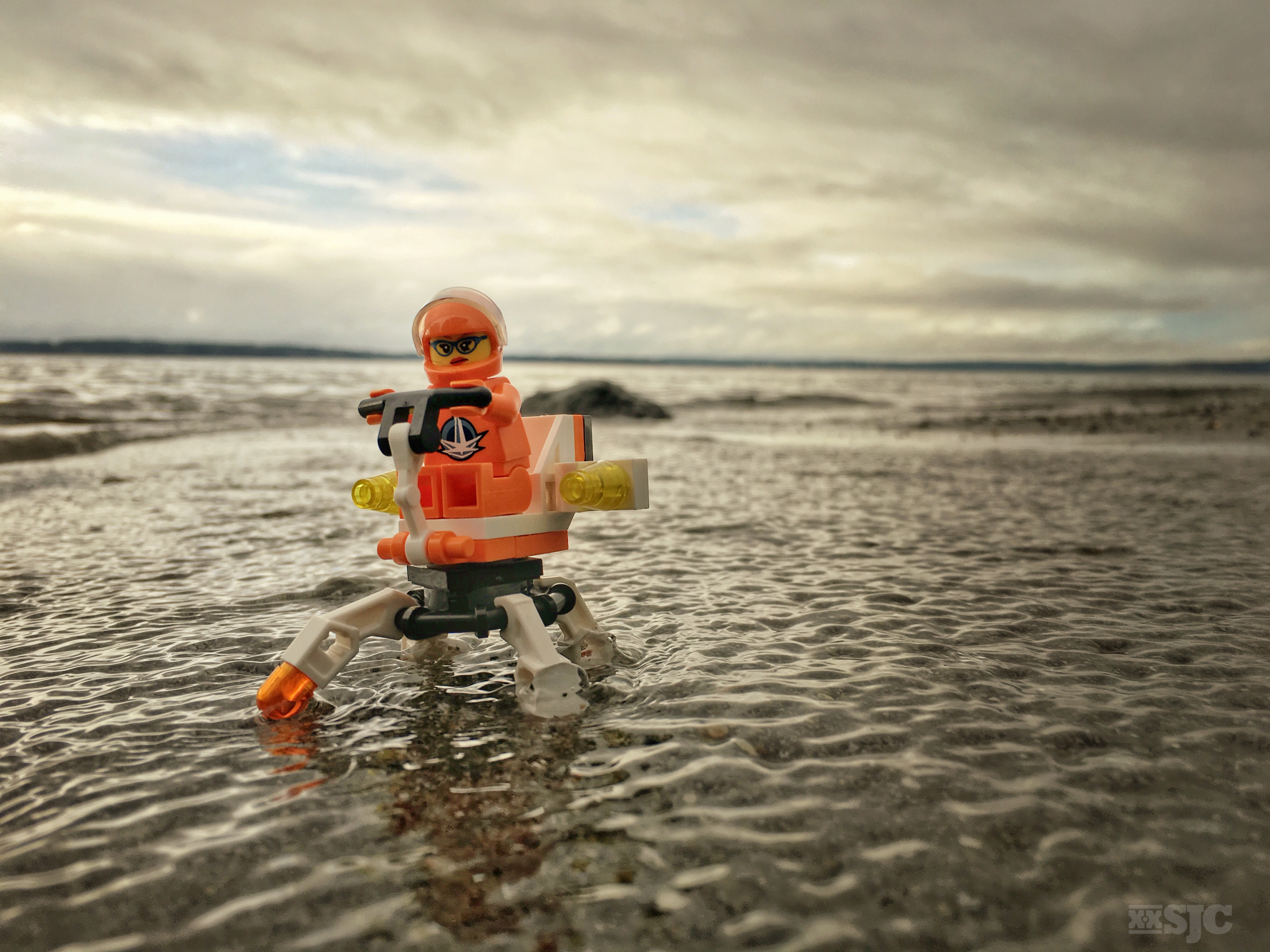 A Female LEGO explorer users her interplanetary explorer to cross a shallow bay of water.