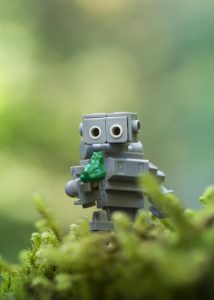 Lego Robot looks at a small LEGO frog in confusion.
