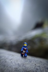 blue LEGO spaceman holds teddybear and looks afraid, taken with a lensbaby by Shelly Corbett