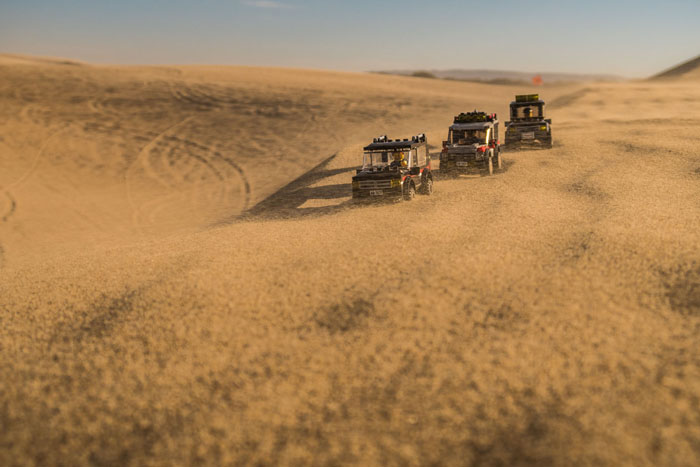 Three LEGO 4x4 trucks out in the windswept dunes