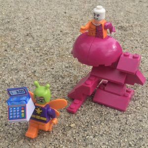 Photo by Adam Ford: Lego minifigure scene: DC comics superhero Metamorpho chasing supervillain Killer Moth, who has stolen an entire cash register.