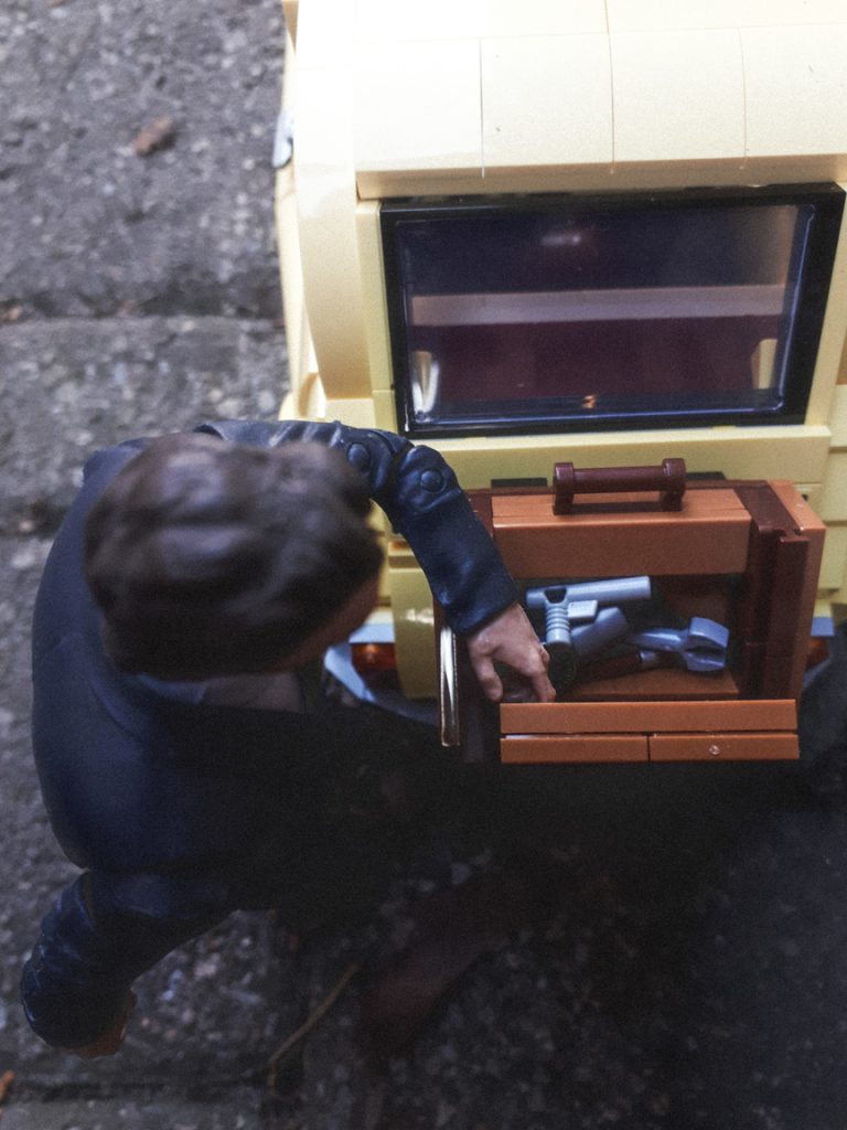 A man looks through a case mounted on the back of the LEGO Fiat 500