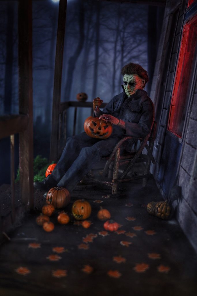 Michael Myers action figure carving pumpkins in rocking chair before Halloween by @tromatic_exposure