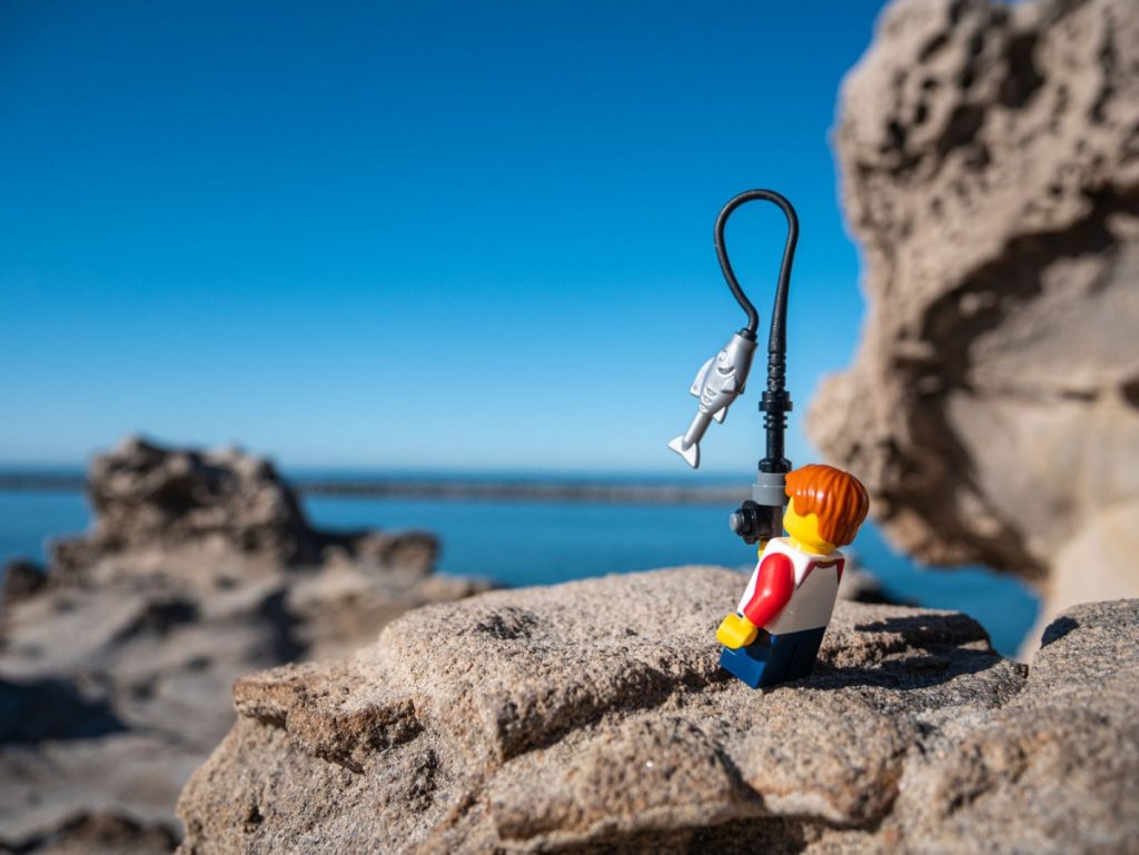 Lego minifig catching fish at the ocean.