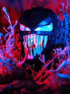 A lego sculpture of Venom in some underbrush with fancy lighting to make it look more scary.