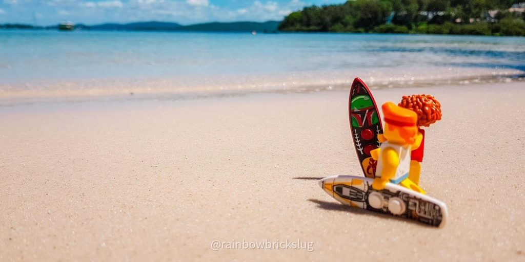 LEGO surfers minifigures with surfboards, standing on the beach