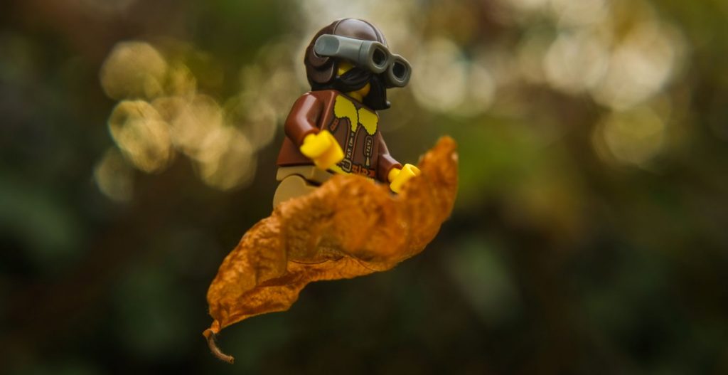 Lego vintage pilot minifigure flyuing on the dry leaf