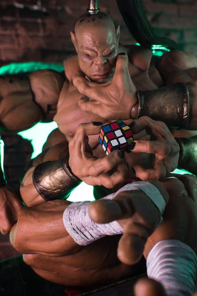 Goro action figure posed as he's trying to solve a Rubik's cube