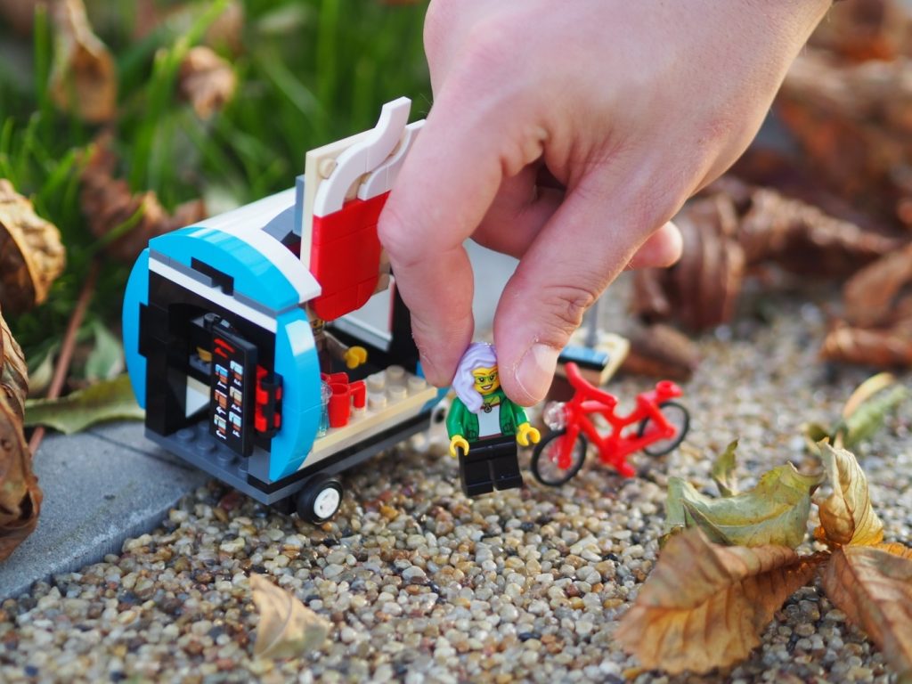 A LEGO coffee cart set with hand holding a female minifigure