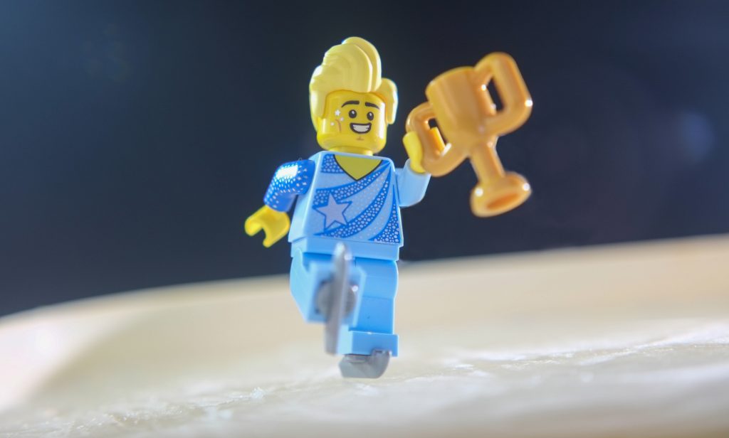 A male figure skating minifigure holding a golden cup