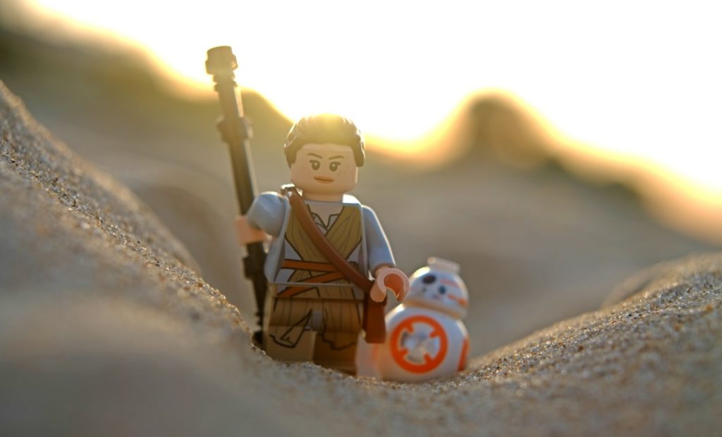 LEGO Rey minifigure on sand, walking toards the camera with LEGO BB8