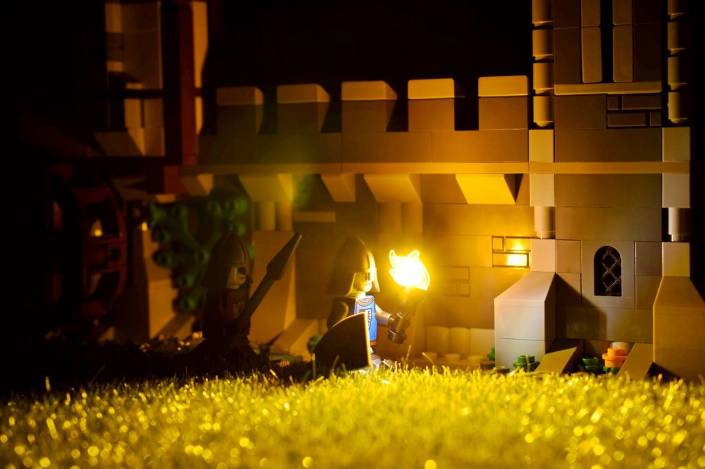 LEGO castle walls lit by the Black Falcon knight holding a torch