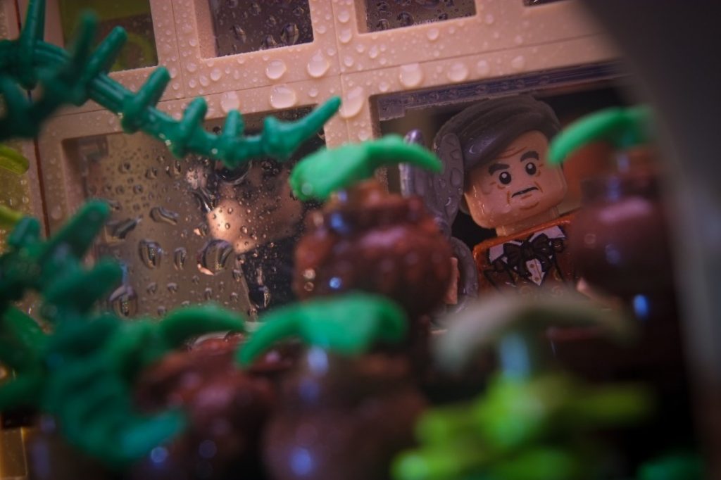 Horace Slughorn LEGO minifigure peeking into the Greenhouse with scissors in his hand.