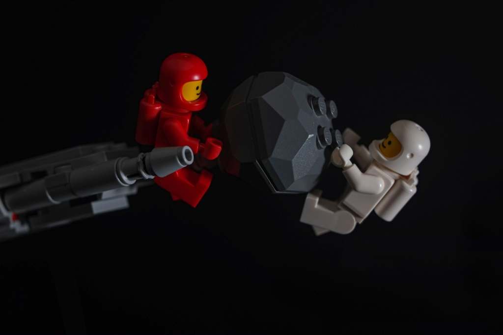 Two classic Lego space spacemen removing the asteroid from the spaceship's prow