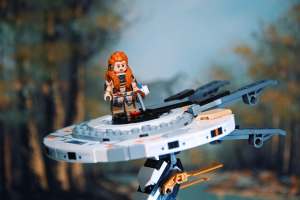 Aloy minifigure with spear and bow, from LEGO Horizon Forbidden West: Tallneck (76989) set, standing on Tallneck's head