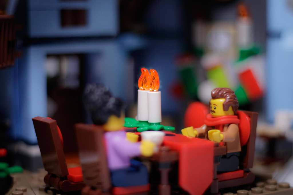 two Lego kinifigures sitting by the brick built table