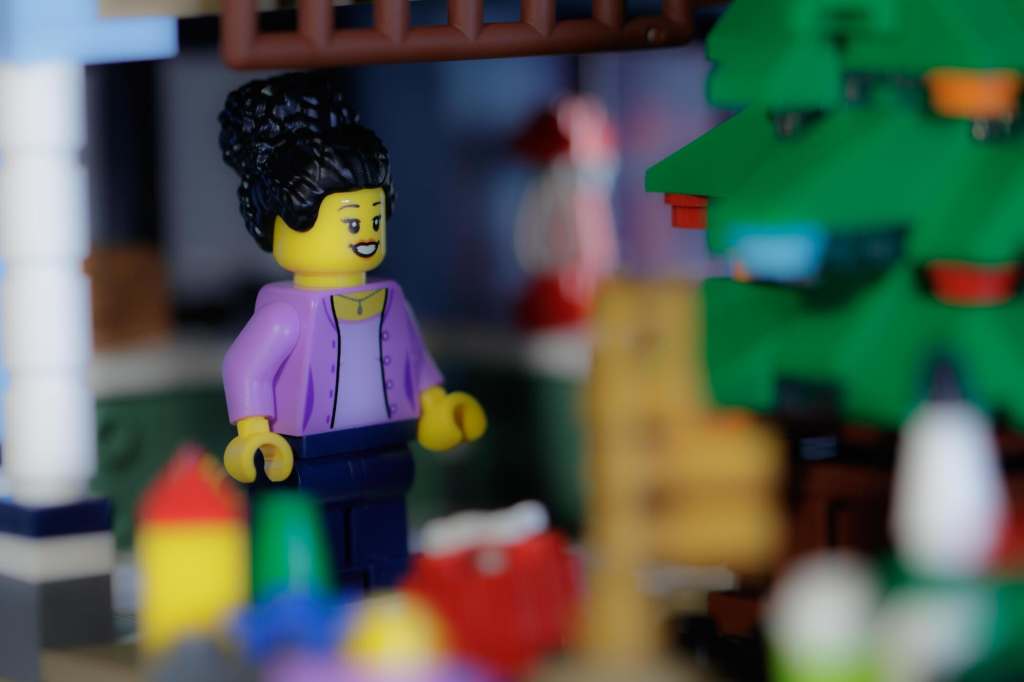a female Lego minifigure looking at brick built Christmas tree