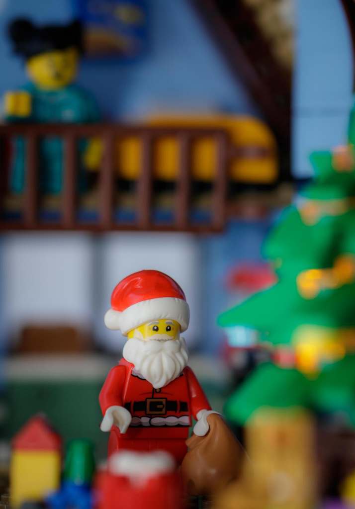 a Lego Santa Claus minifigure putting presents under brick built Christmas tree
