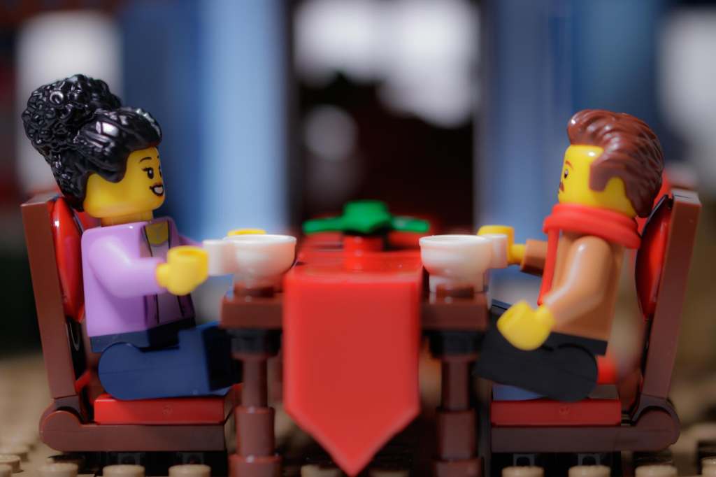 a female and male Leg minifigures sitting by the brock built table