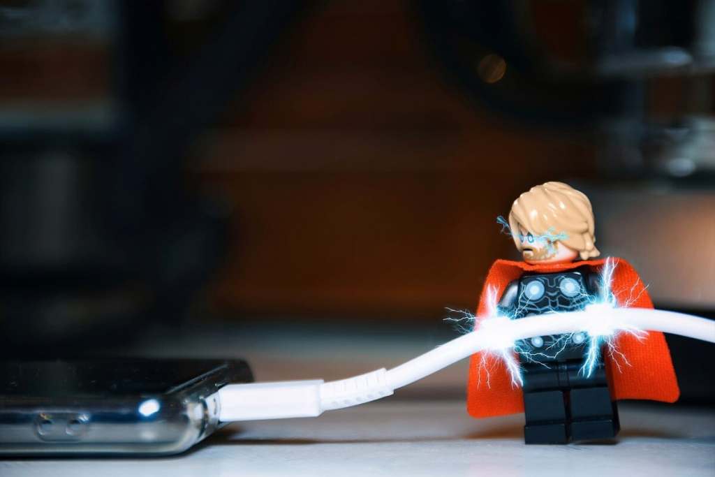 LEGO Thor minifigure holding a phone charging cable attached to phone with electric discharge all around.
