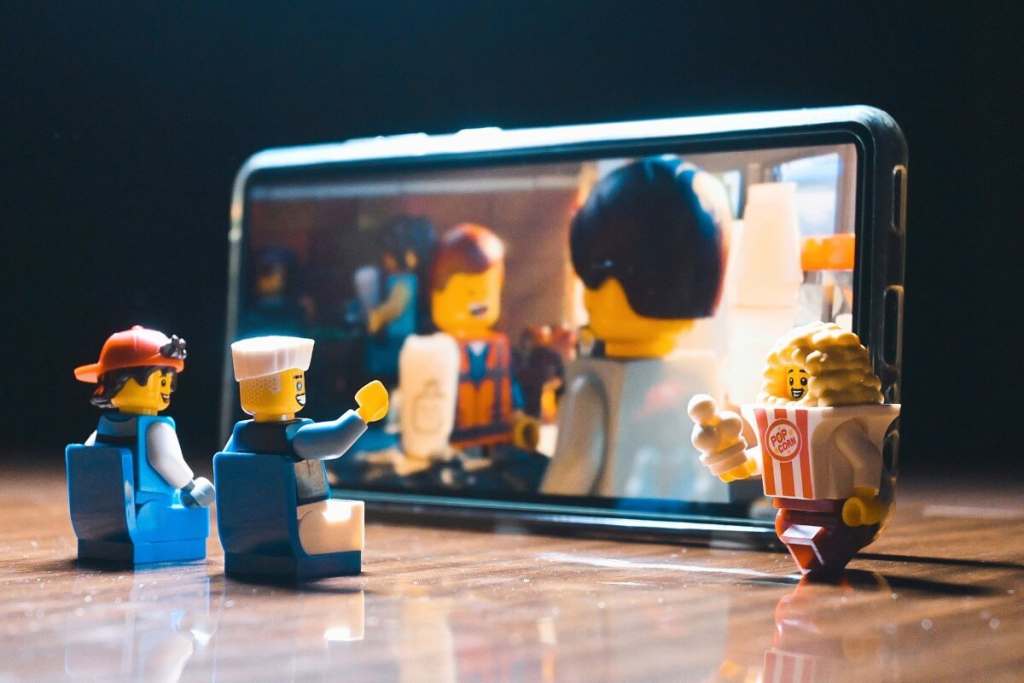 LEGO minifigures sitting inf ront of the smartphone screen in cinema-like style. 