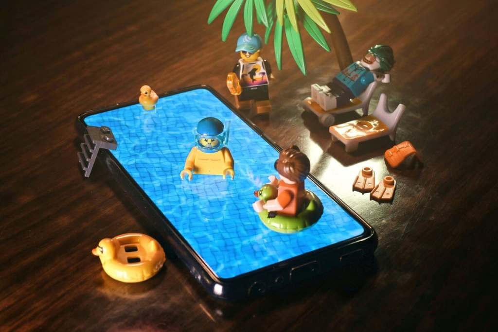 LEGO minifigures partying by the smartphone screen with pool surface display.