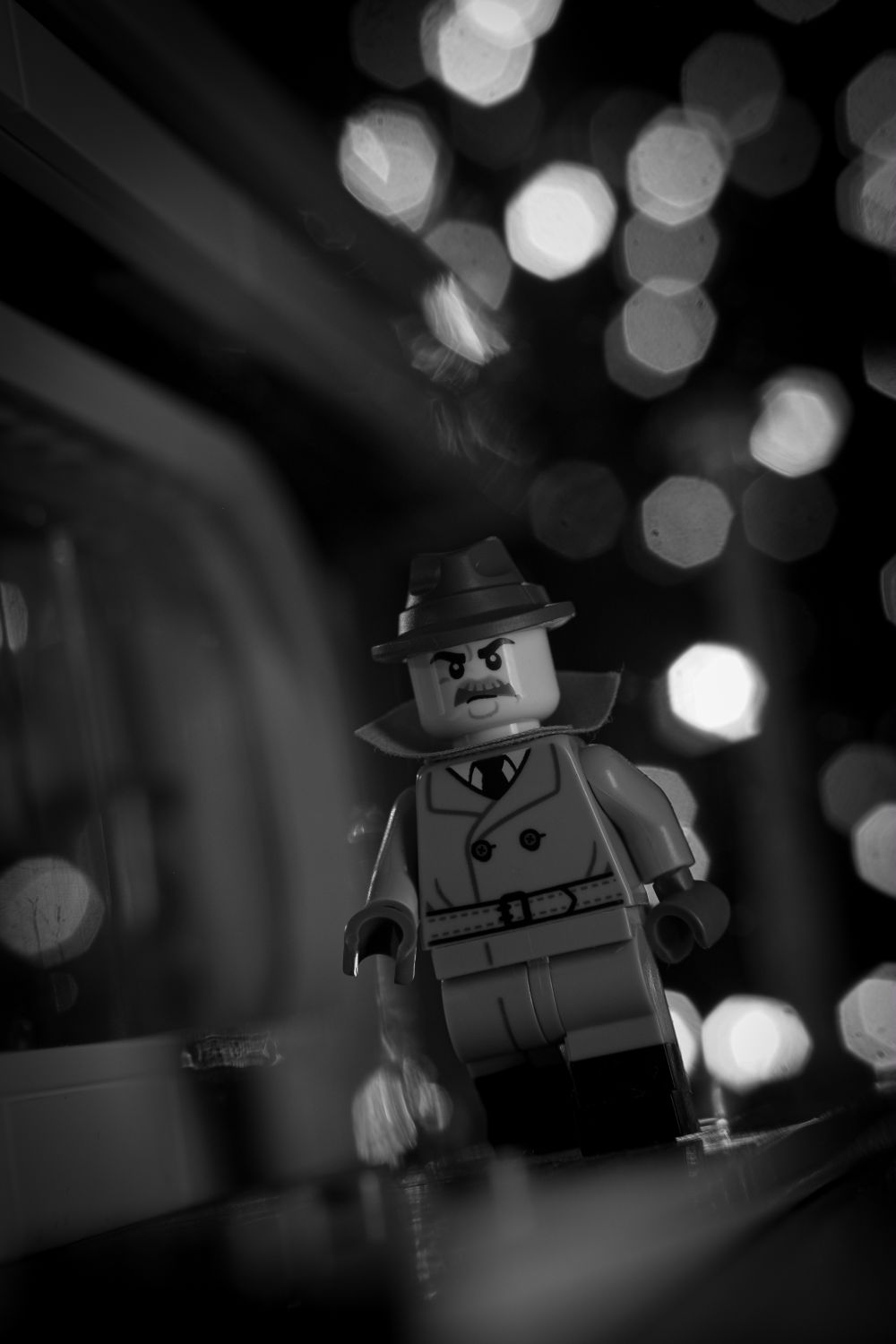 A LEGO noir detective in black and white with bokeh in the background.