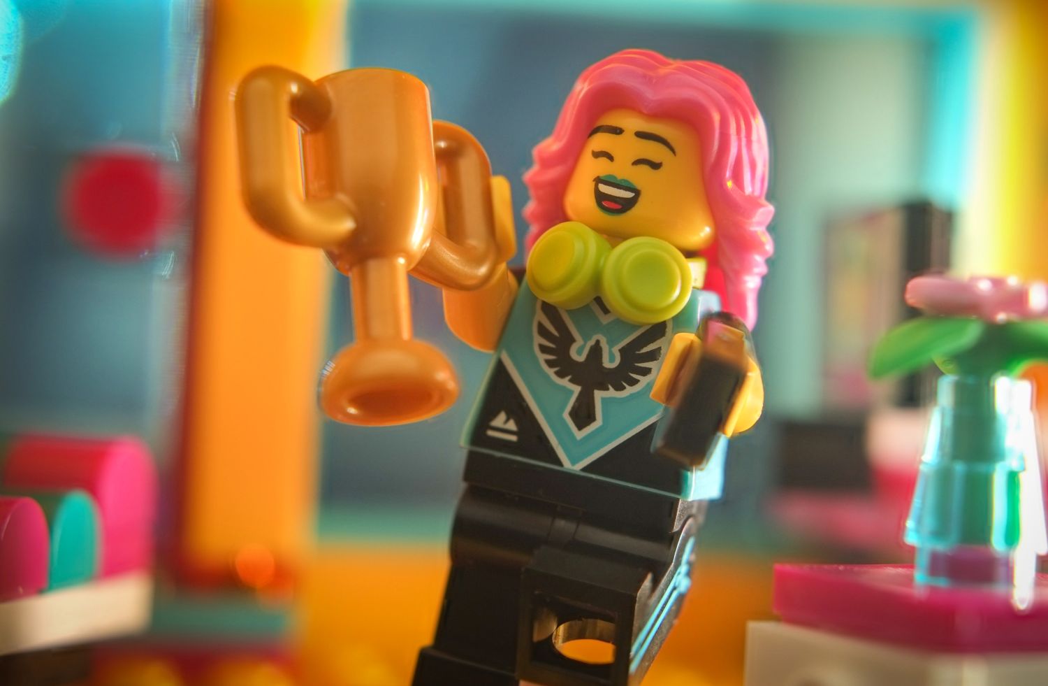 A LEGO video player minifigure smiling, holding a golden cup in her hand.