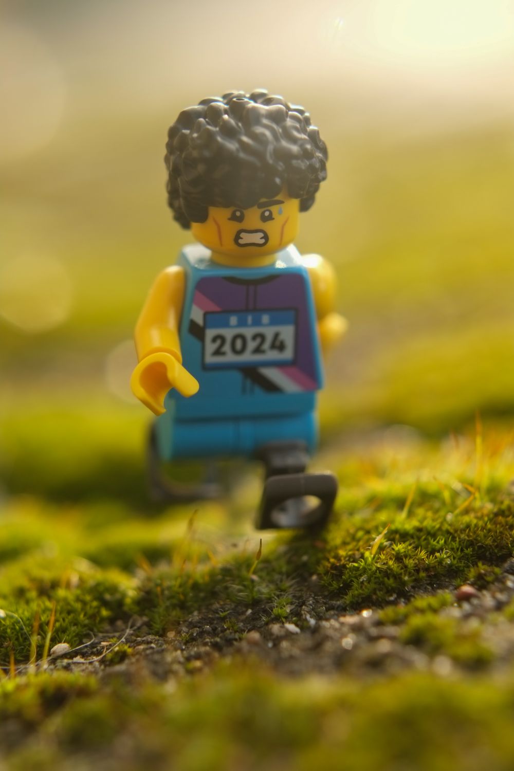 A LEGO paralympic athlete with prosthetic legs running on the grass.