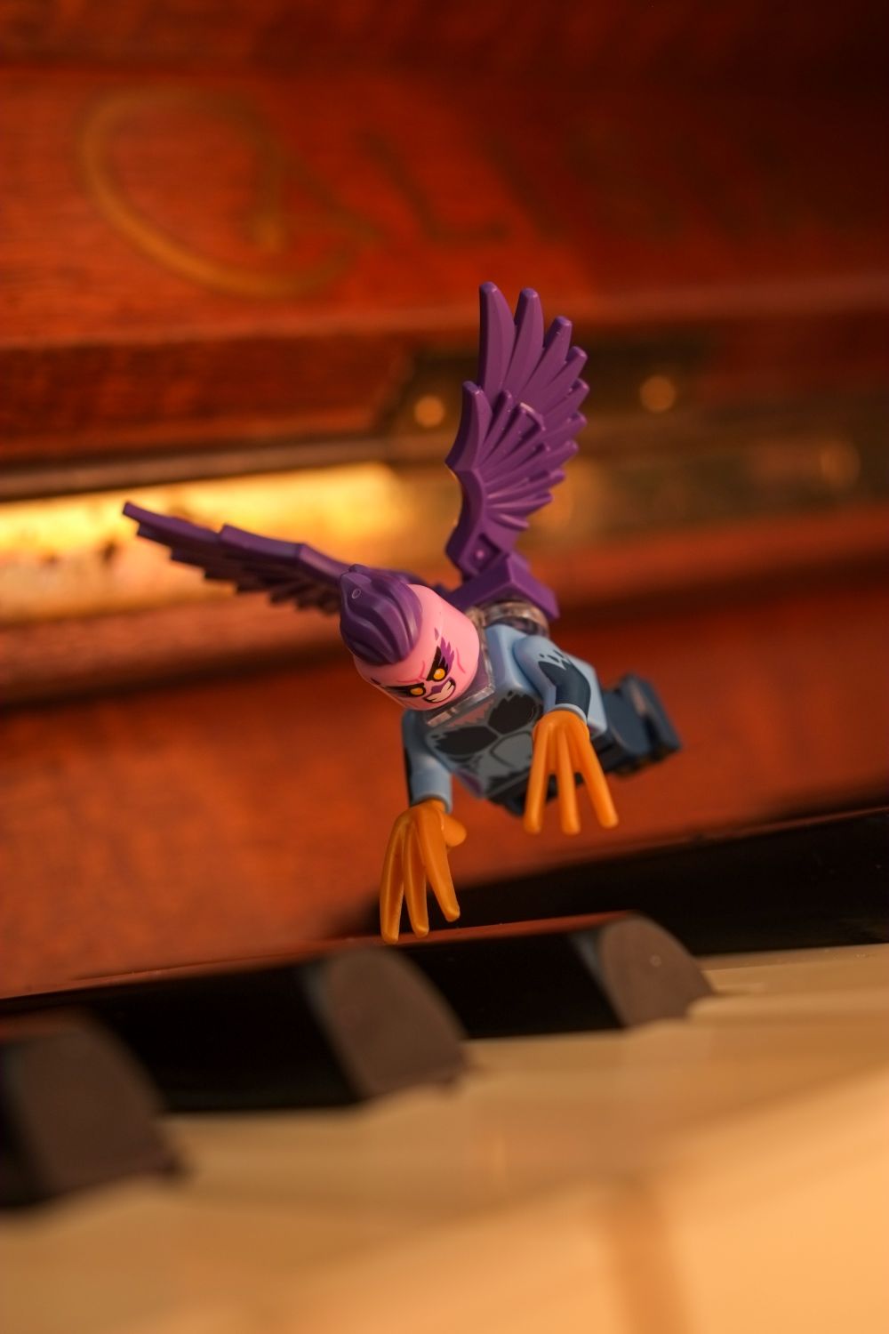 A LEGO harpy minifigure flying,over the piano keys.