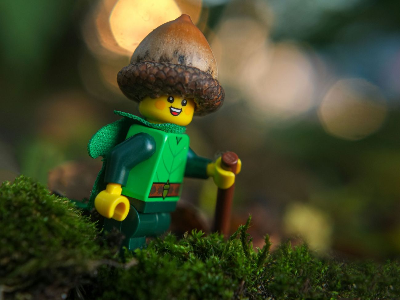 A happy Forest Elf LEGO minifigure walks through the forest wearing an acorn hat.