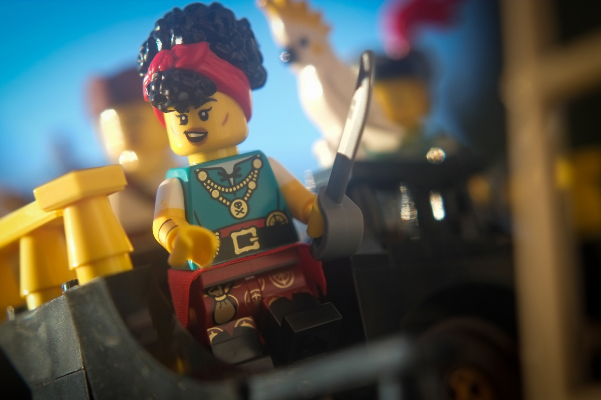 Pirate Quartermaster minifigure laughing as she walks down the stairs from the ship's aftercastle, looking out of frame